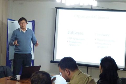 A man giving a presentation on the structure of the IT market in a conference room.
