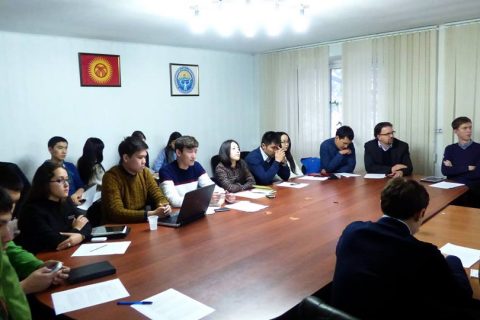 A group of people sitting around a conference table in a meeting room.