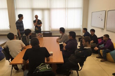 A group of people sitting around a table in a classroom setting, discussing a topic.