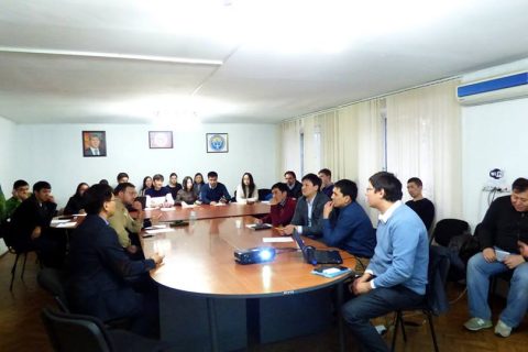 A group of people sitting around a table in a conference room.