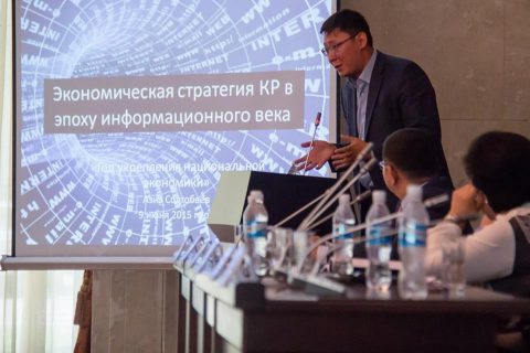 Speaker presenting at a conference on economic strategy in the information age.