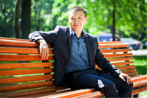 A man in a suit sitting on a bench in a park.