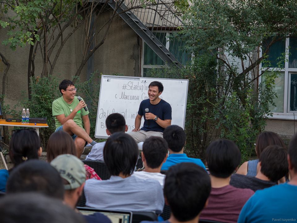 A group of people sitting in a circle, listening to two speakers at a Startup Tuesday event.