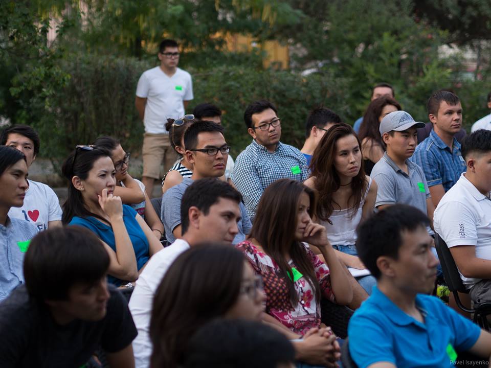 A group of people sitting in an outdoor setting, possibly attending a workshop or event.
