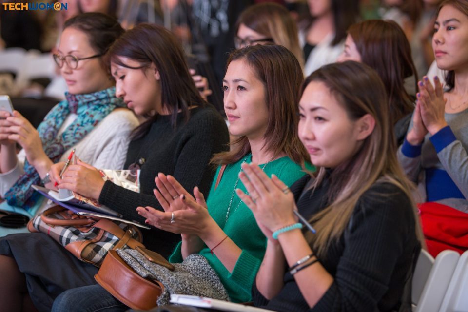 Attendees at a tech event in Bishkek, Kyrgyzstan, applauding and taking notes.