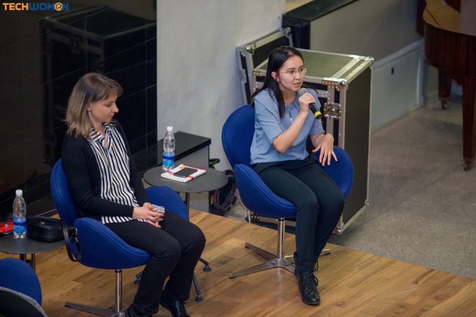Two women seated on a stage during a panel discussion at a tech event.
