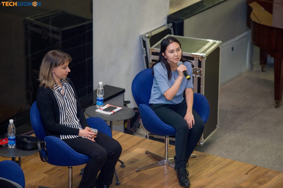 Two women seated on stage during a panel discussion at a tech event.