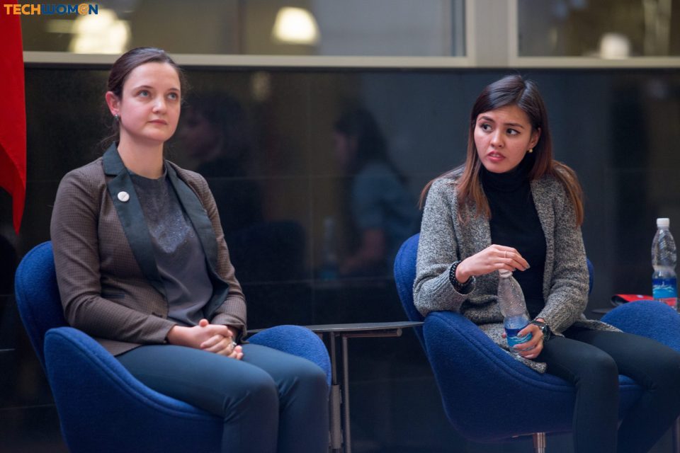 Two women seated in blue chairs during a discussion at an event organized by KG Labs Foundation.