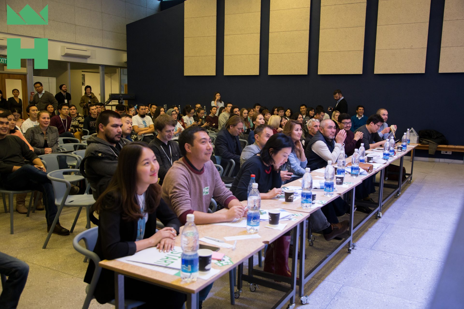 Participants seated at tables in a conference room, engaged in a workshop or training session.