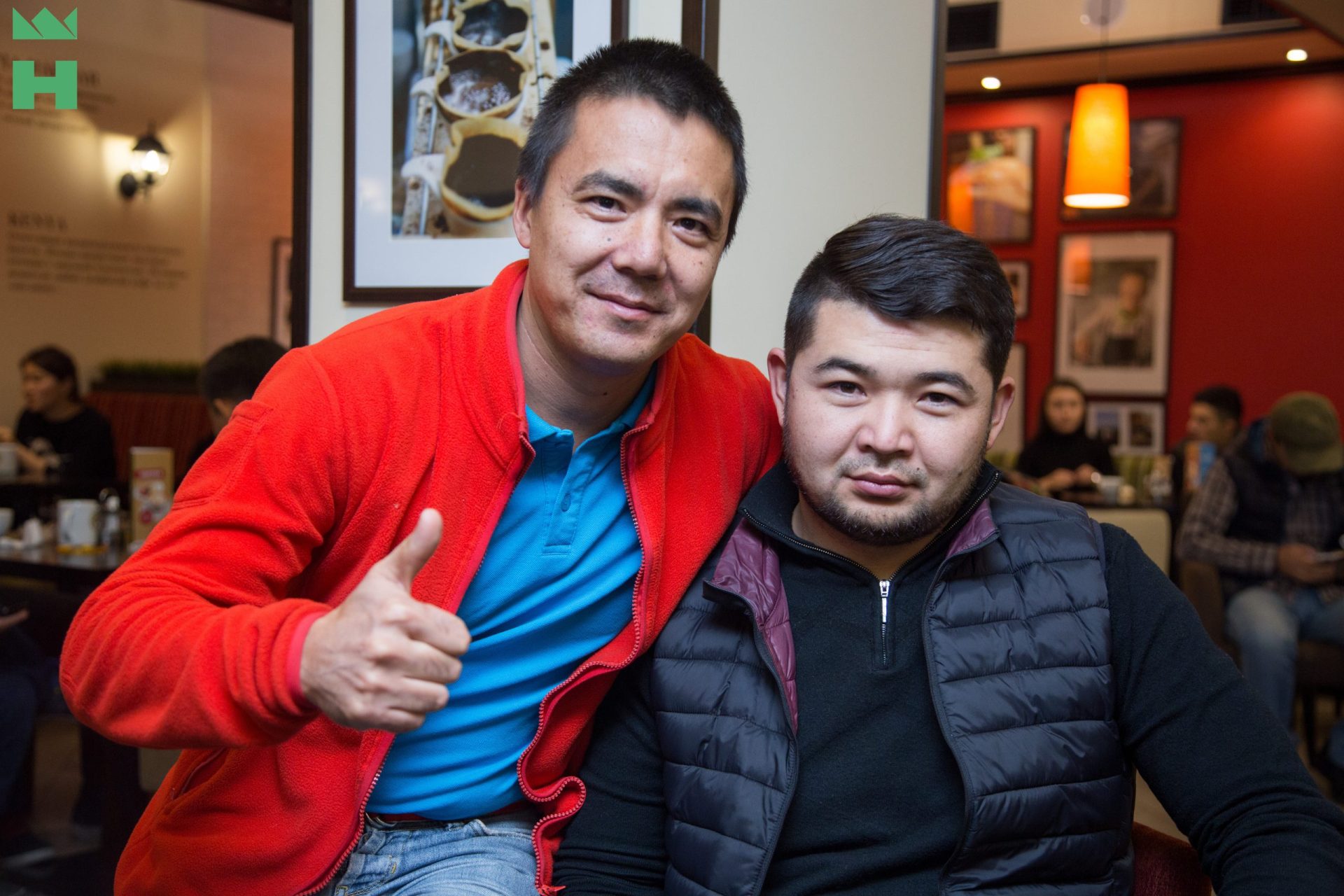 Two men posing for a photo in a coffee house.