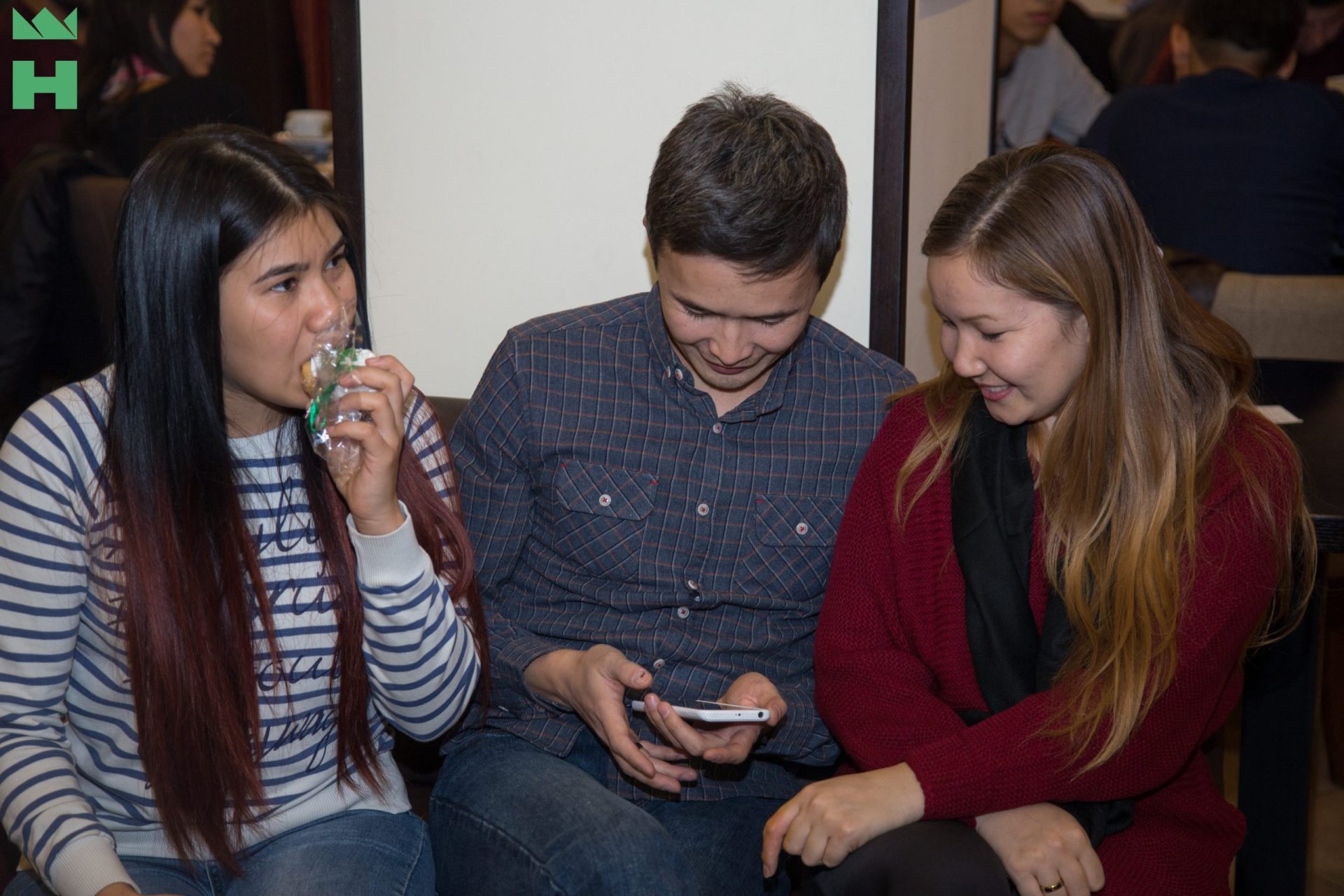 Three individuals engaged in a casual conversation at an event in Bishkek, Kyrgyzstan.