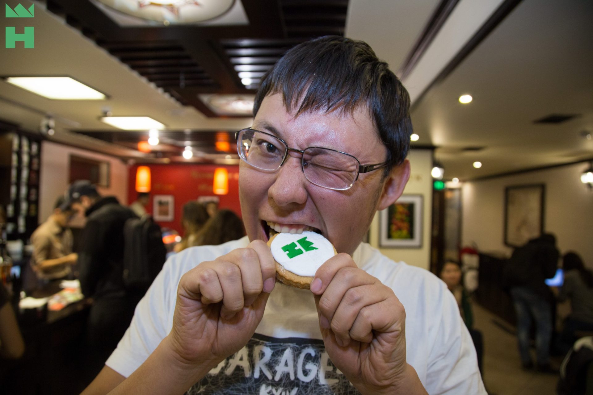 A person enjoying a cookie with a green logo in a restaurant setting.