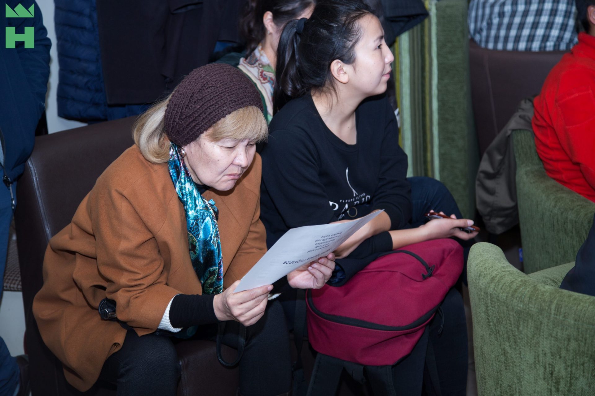 Participants in a workshop or conference in Bishkek, Kyrgyzstan, engaged in discussion and reviewing documents.