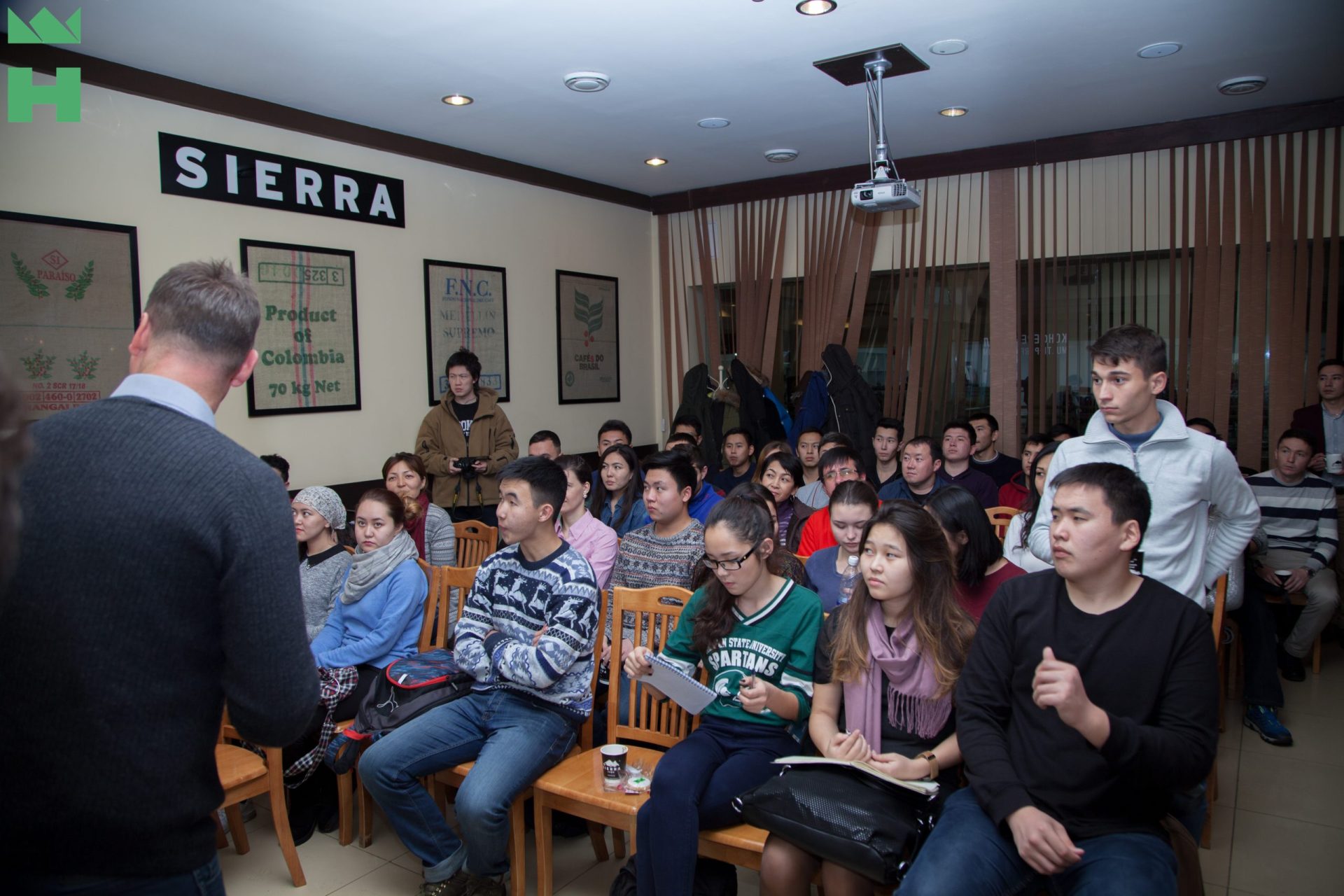 A group of people sitting in a room, attentively listening to a speaker.