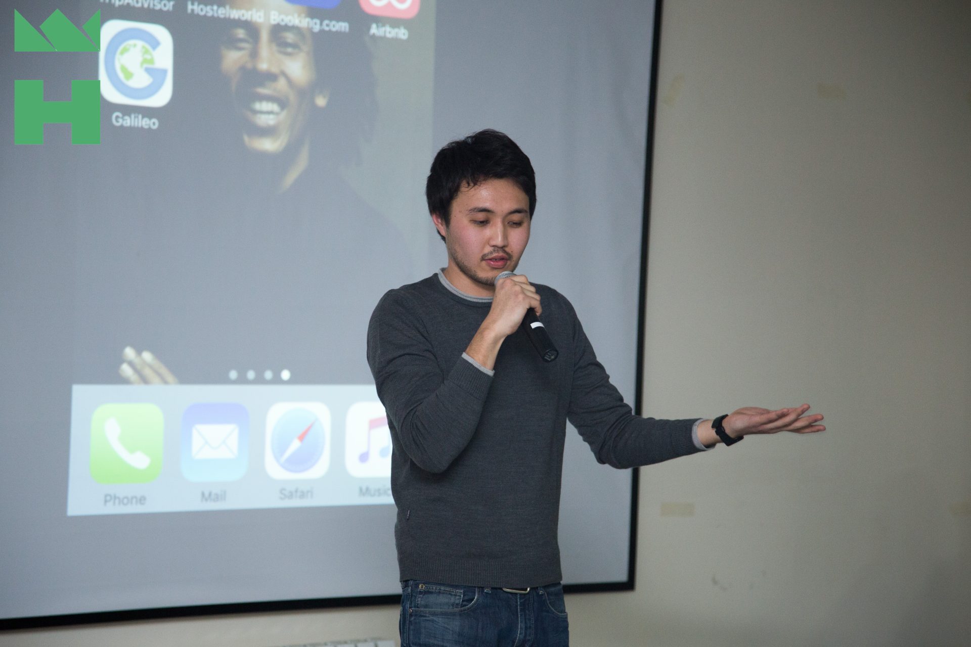 A person giving a presentation in a classroom setting with a projector screen displaying various apps.
