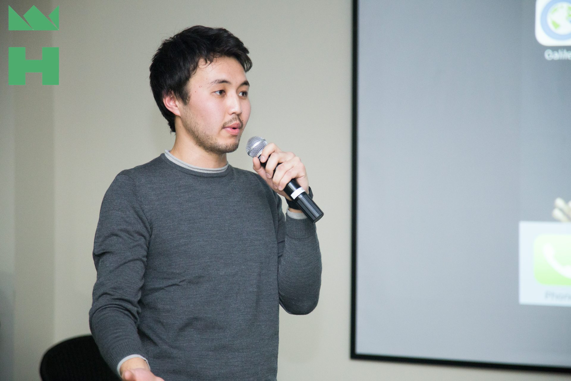 A person speaking into a microphone in a conference setting.
