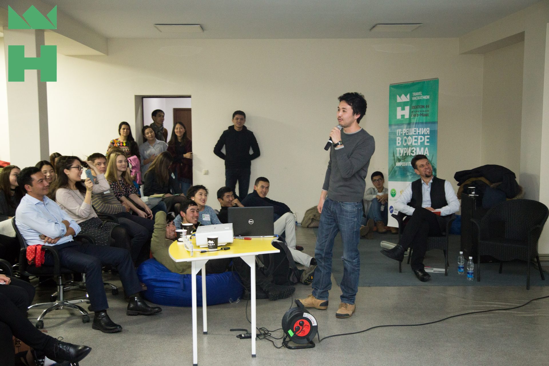 A group of people gathered in a room for a workshop or event, with one person speaking into a microphone.