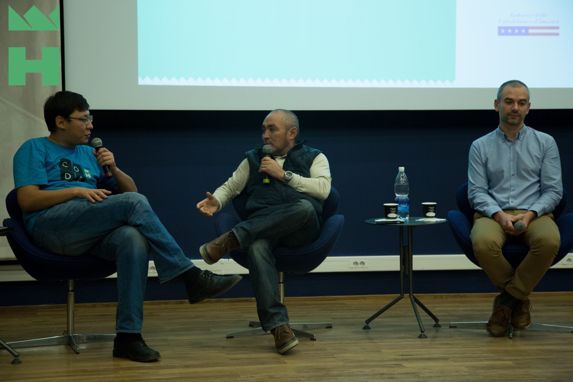 Three individuals seated on stage during a panel discussion at an event organized by KG Labs Foundation in Bishkek, Kyrgyzstan.