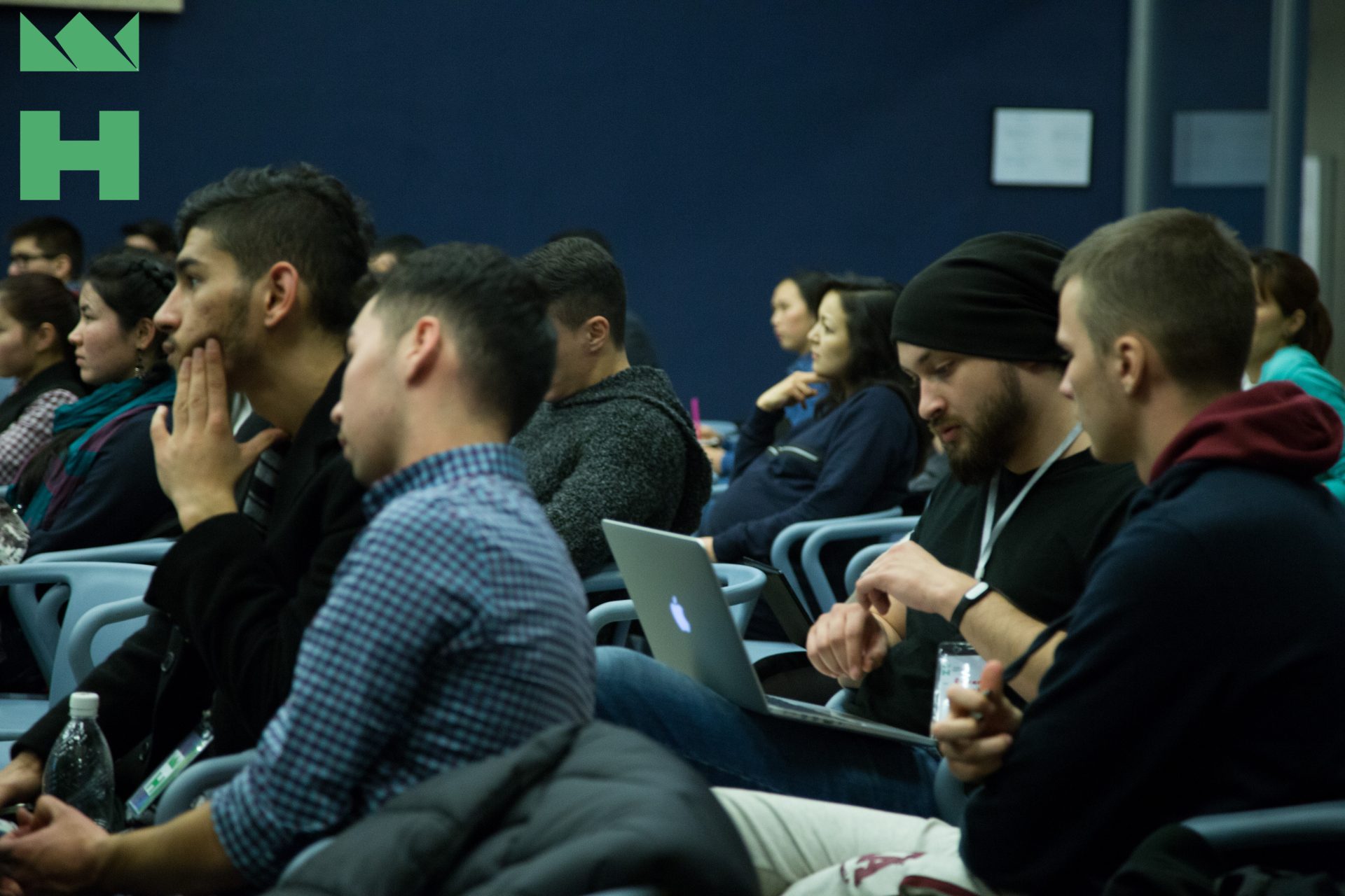 Participants attentively listening to a presentation in a conference room.