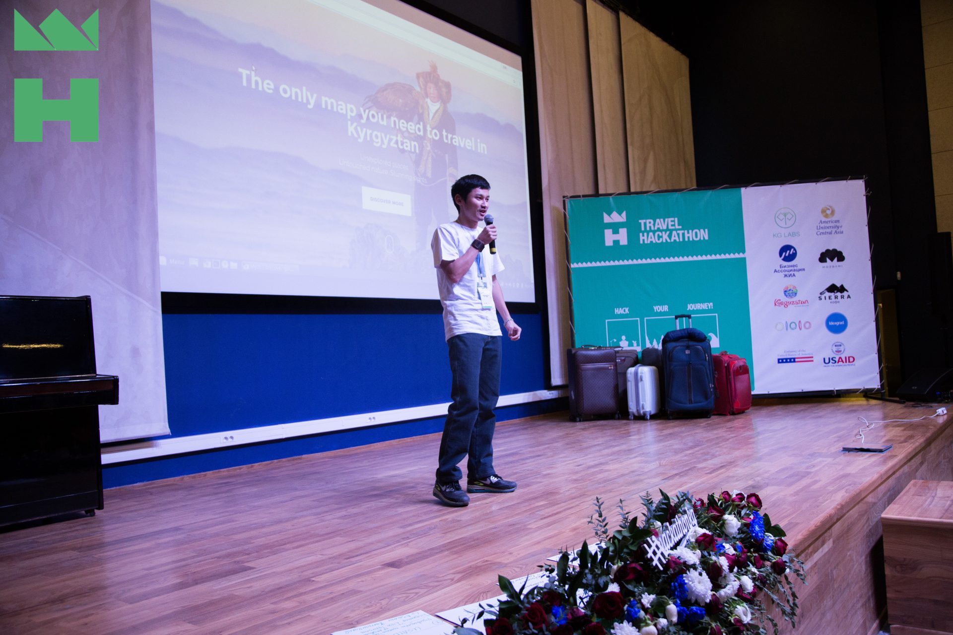 A person speaks on stage at a Travel Hackathon event in Bishkek, Kyrgyzstan.
