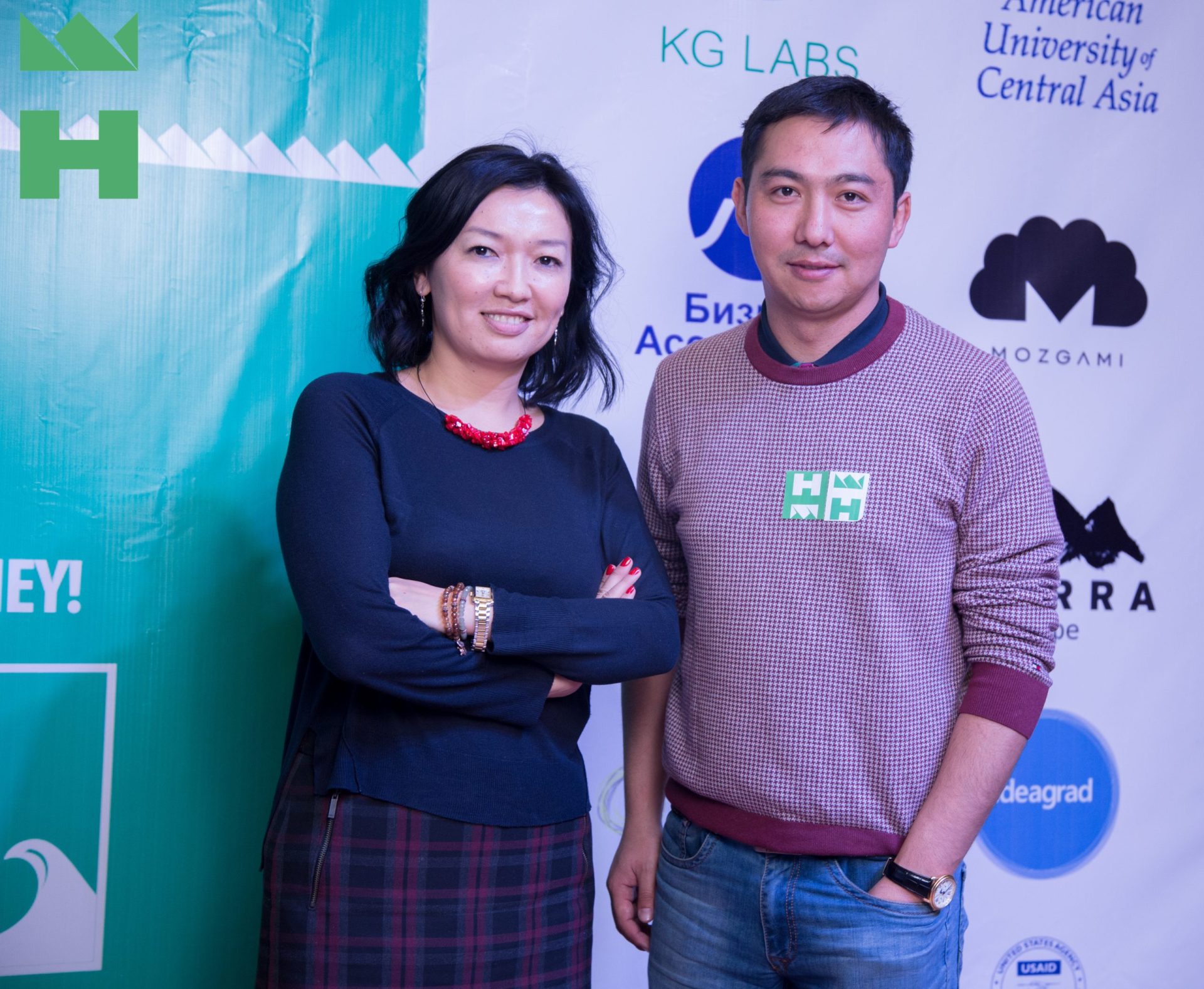 Two individuals posing for a photo in front of a KG Labs Foundation banner.