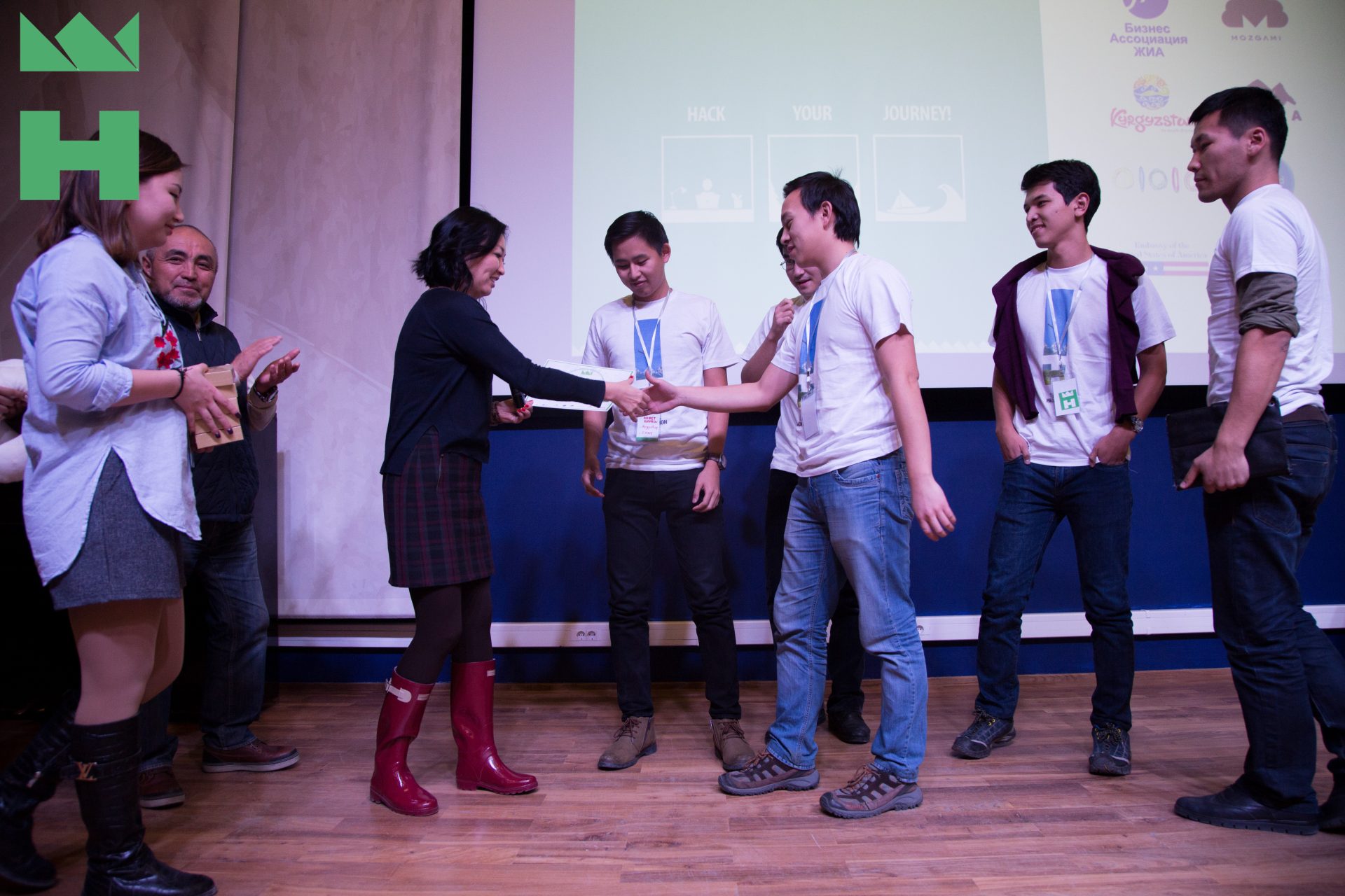 Participants shaking hands on stage at a KG Labs Foundation event in Bishkek, Kyrgyzstan.