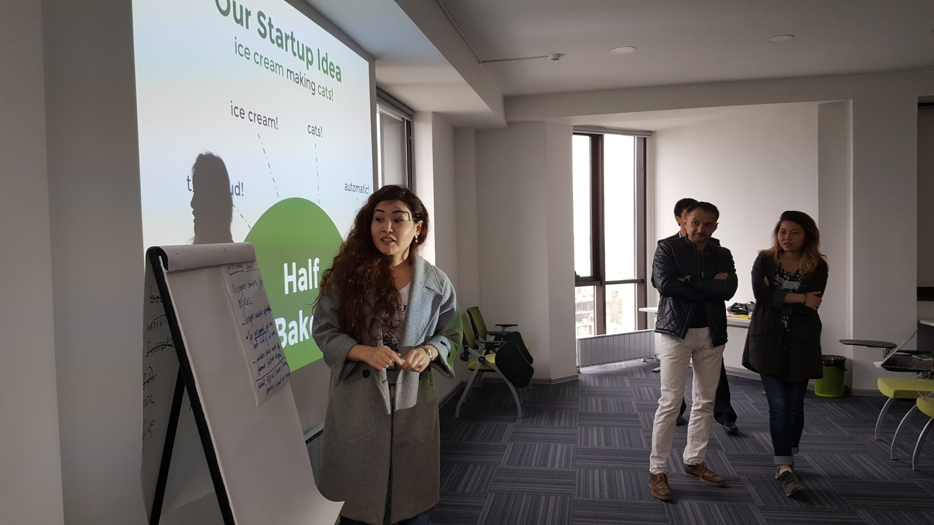 A woman presents a startup idea slide in a workshop setting.