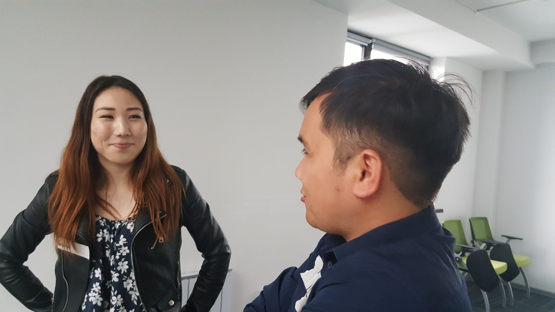 Two individuals engaged in conversation in a modern office setting.