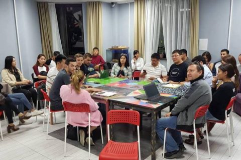 A group of people sitting around a table in a meeting room.