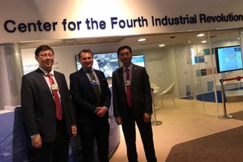 Three men in suits stand in front of a sign for the Center for the Fourth Industrial Revolution.