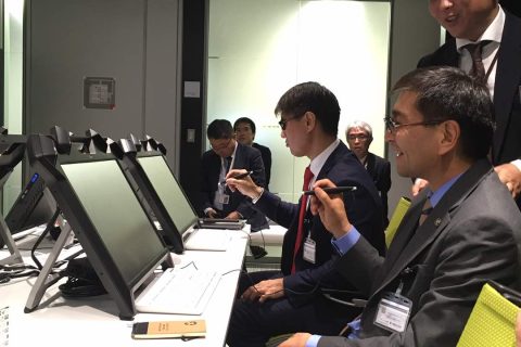 Group of professionals in suits working at computers in a conference room.
