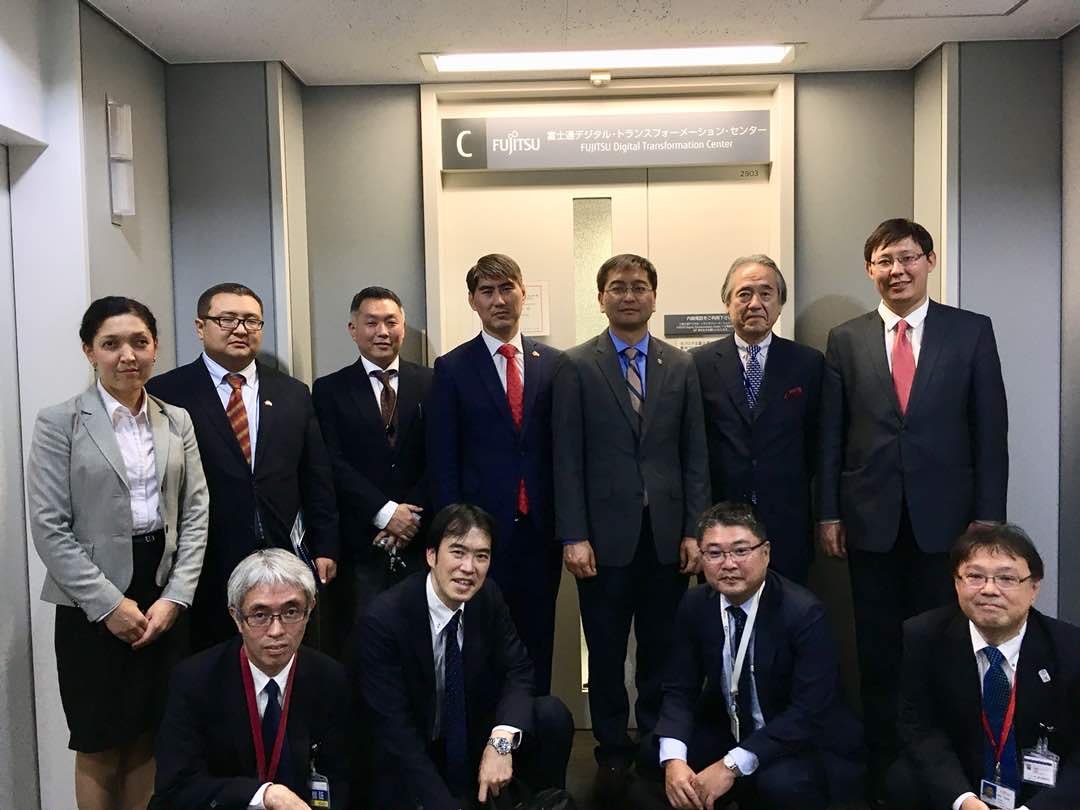 A group of professionals poses for a photo in front of a door labeled 'Fujitsu Digital Transformation Center'.