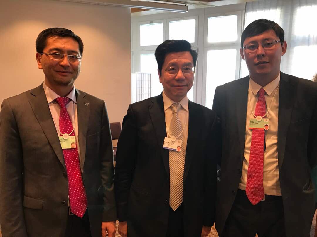 Three men in suits pose for a photo at an event.