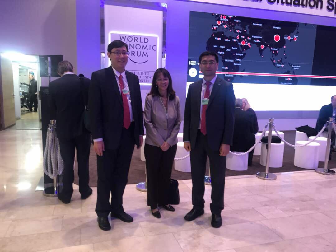 Three individuals pose for a photo at the World Economic Forum.