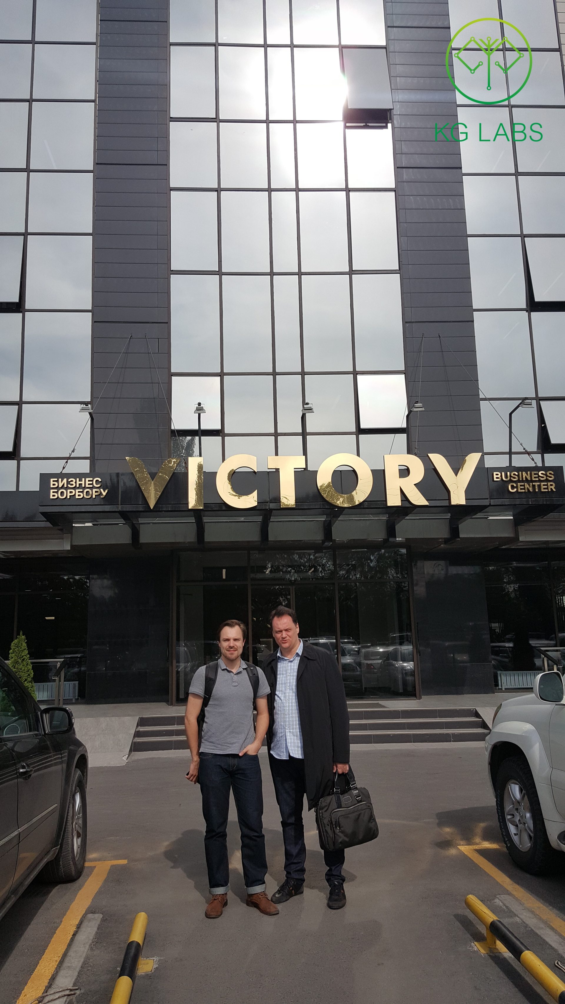Two individuals standing in front of the Victory Business Center in Bishkek, Kyrgyzstan.