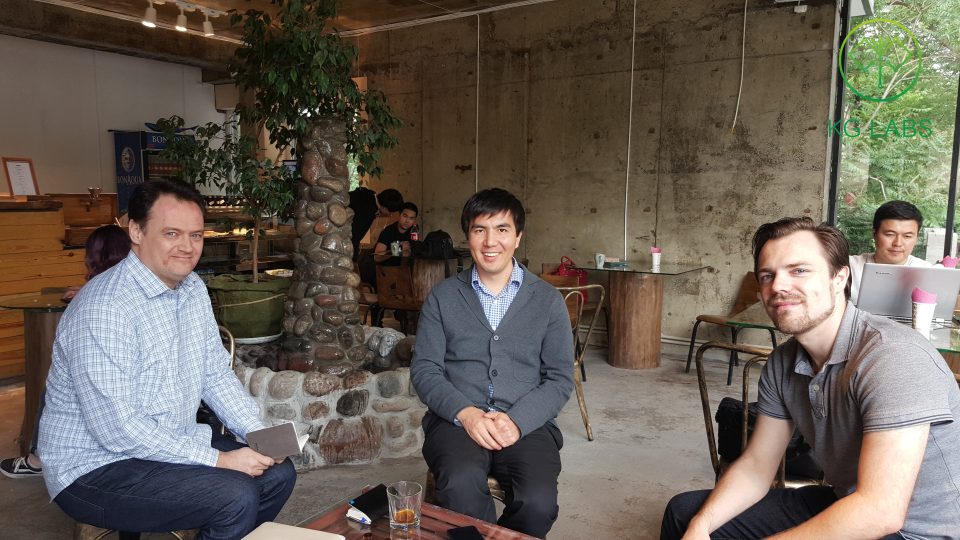 Three individuals sitting in a casual indoor setting, possibly a cafe or meeting space.