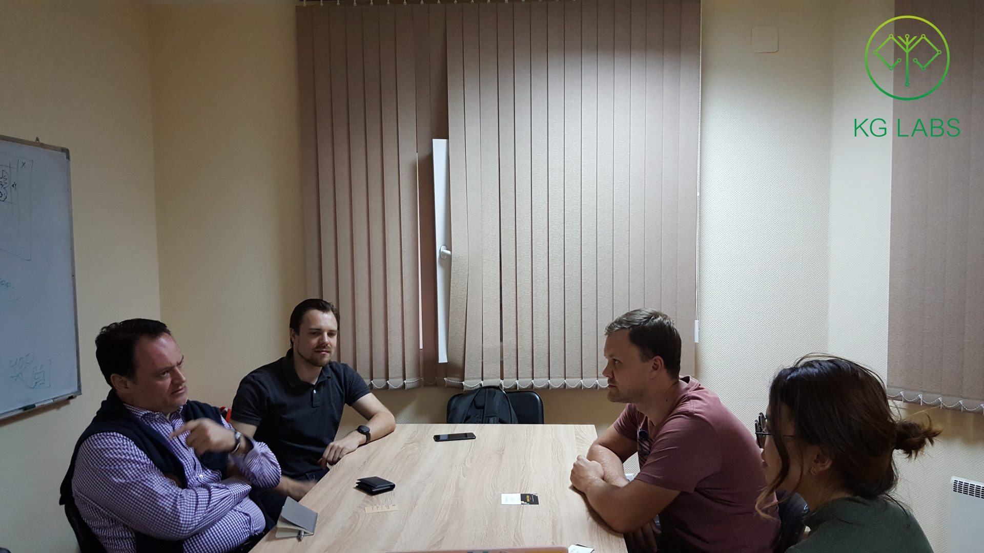 Four individuals engaged in a discussion at a conference table in a meeting room.