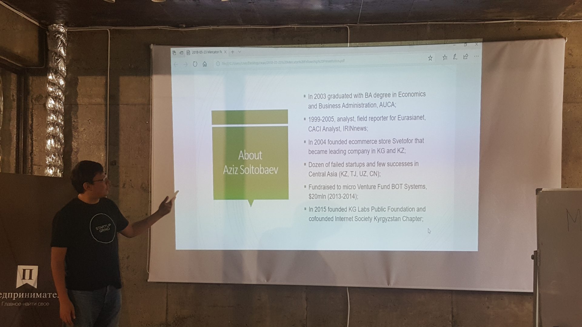 A person giving a presentation on a screen with information about Aziz Soltobaev.