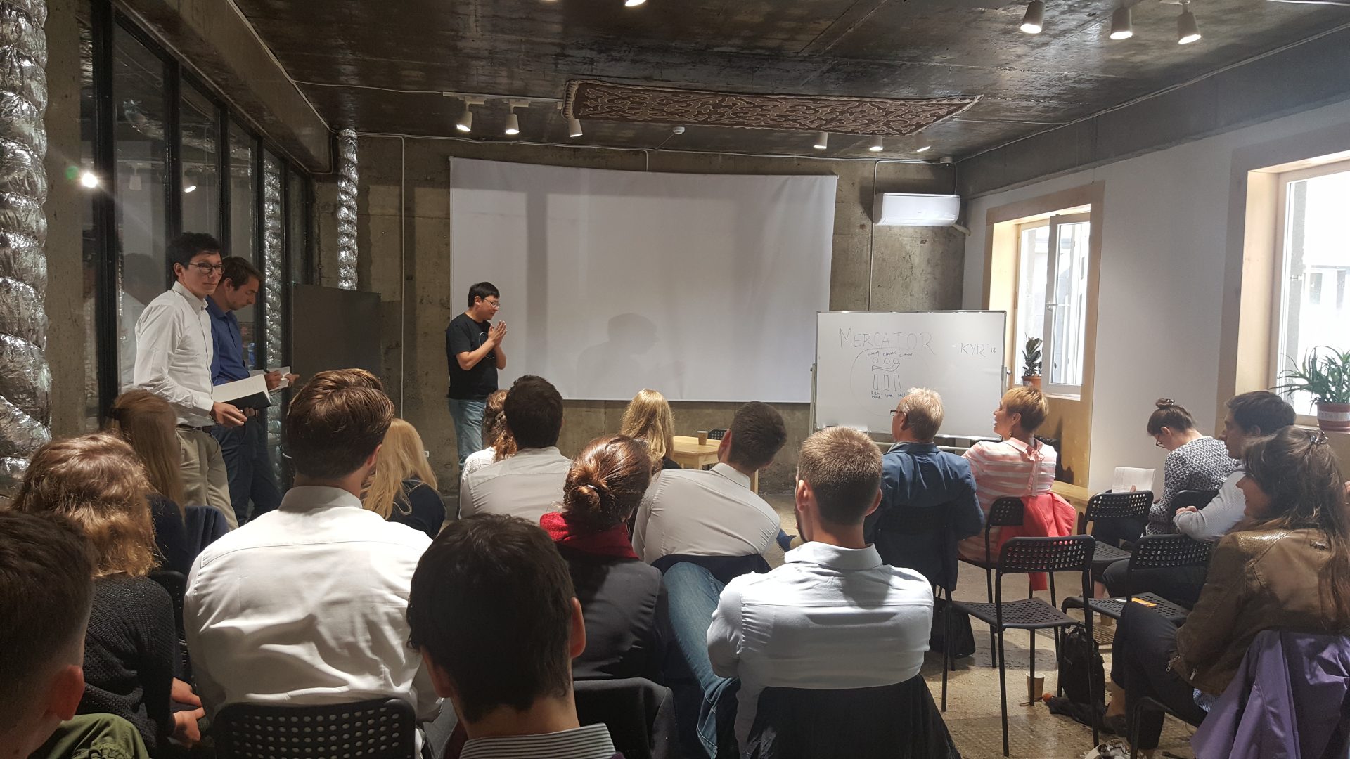 A group of people is gathered in a room for a workshop or presentation.
