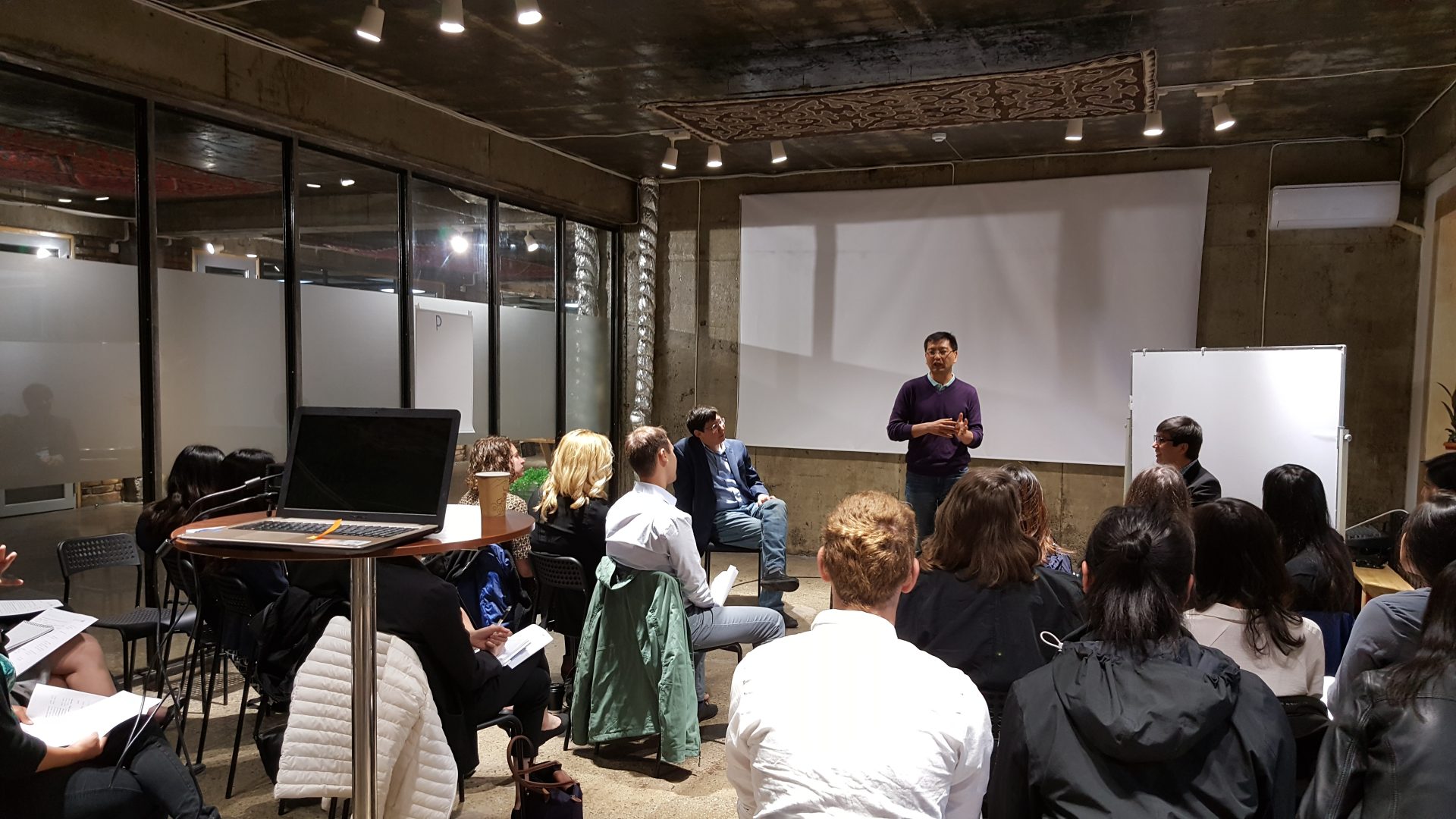 A group of people is gathered in a room for a workshop or presentation.