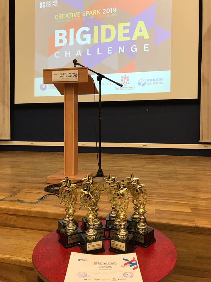 A podium and trophies on a stage with a banner reading 'Creative Spark 2019 Big Idea Challenge'.