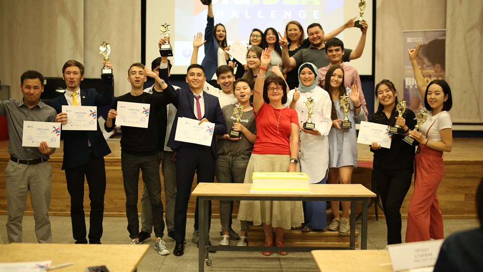 A group of people celebrates with trophies and certificates at an award ceremony in Bishkek, Kyrgyzstan.