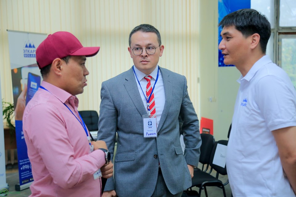 Three men in a discussion at an event in Bishkek, Kyrgyzstan.
