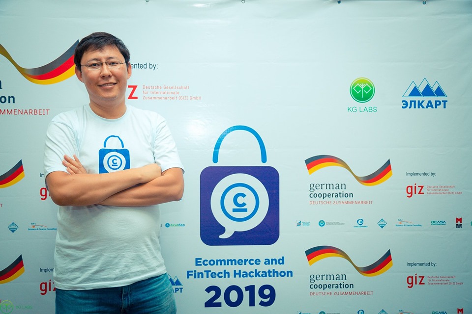 A man stands in front of a banner for the Ecommerce and Fintech Hackathon 2019 in Bishkek, Kyrgyzstan.