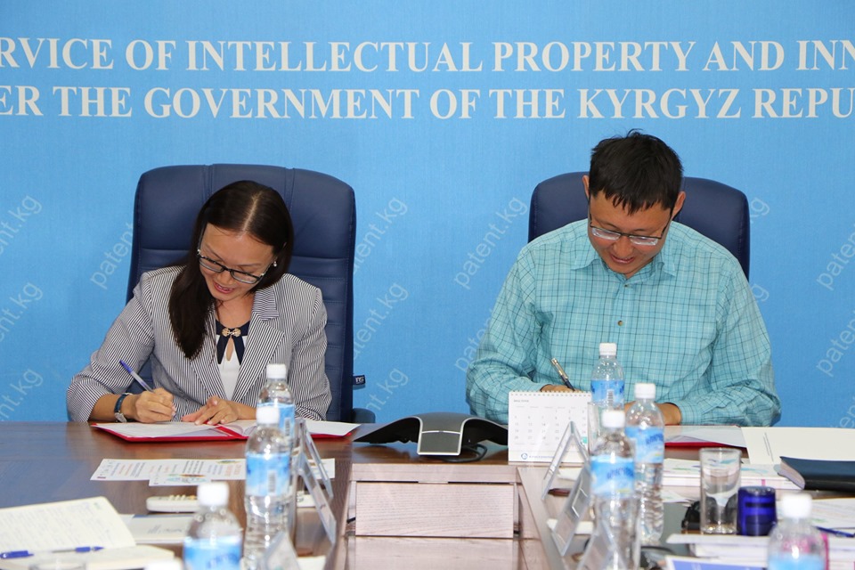 Two individuals are seated at a table in a meeting room with a backdrop that reads 'Service of Intellectual Property and Innovation under the Government of the Kyrgyz Republic'.