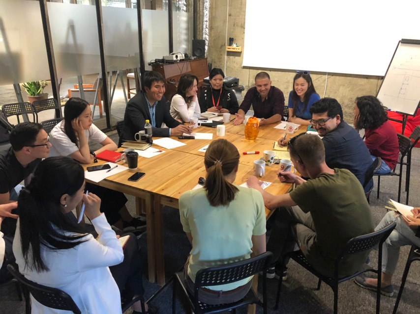 A group of people engaged in a discussion around a table in a conference room.
