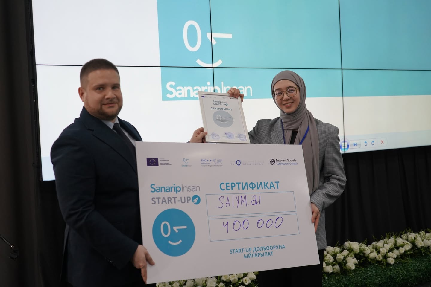 Deputy Minister of Digital Development of the Kyrgyz Republic, Klim Omelchenko, awarding the SalymAI team for their AI-driven tax-assistant prototype.